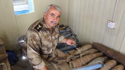 Lt Colonel Najmaldin next to defused mortar rounds turned into IEDs by ISIL. He holds a pressure activated detonator. Florian Neuhof for The National