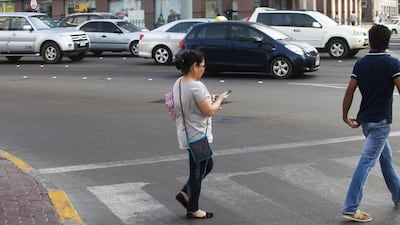 A woman puts herself at risk by crossing at the junction of Electra Street and Muroor Road, in Abu Dhabi city, while texting. Lee Hoagland / The National