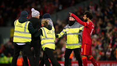 A pitch invader approaches Liverpool's Mohamed Salah after the Premier League match at Anfield, Liverpool.