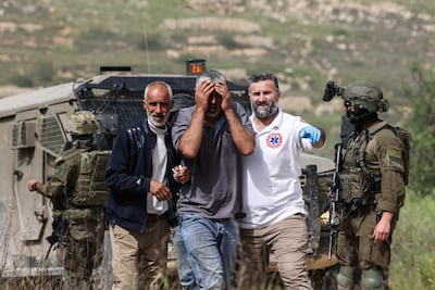 Israeli soldiers stand by as Palestinian medics assist a man who was reportedly attacked with pepper spray by Jewish settlers while he worked on his farmland in the West Bank. AFP