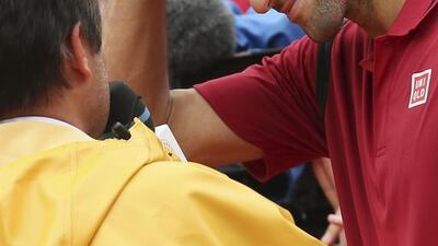 Serbia’s Novak Djokovic wears the rain cap he took from TV journalist Fabrice Santoro, left, after winning his fourth-round match against Spain’s Roberto Bautista Agut. David Vincent / AP Photo