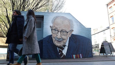 People walk past a mural of Captain Tom Moore by street artist Akse P19 in Manchester's North Quarter. AP Photo