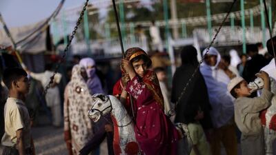 A girl sits on a merry-go-round, hoping for a free ride in Rawalpindi, Pakistan.