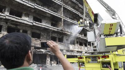 An onlooker photographs Dubai Civil Defence as they douse the building.