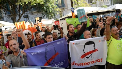 People hold placards reading "Democracy" as they protest after the arrest of a Catalan official during a search by Spain's Guardia Civil police.