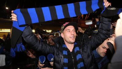 Lukas Podolski holds up a blue and black scarf - Inter Milan colours - on his arrival in Milan, Italy on Friday, purportedly to sign a loan deal with the club. Matteo Bazzi / EPA / January 2, 2015