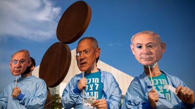 Israeli demonstrators hold masks depicting Israeli Prime Minister Benjamin Netanyahu and Defense Minister Benny Gantz in Tel Aviv, December 2, 2020. AP Photo