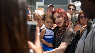 Priscilla Presley, center right, former wife of Elvis Presley, holds a child while greeting fans at Elvis Presley's Memphis near Graceland, Elvis Presley's Memphis home, on Tuesday, Aug. 15, 2017, in Memphis, Tenn. Fans from around the world are at Graceland for the 40th anniversary of his death. Presley died August 16, 1977. Brandon Dill / AP photo