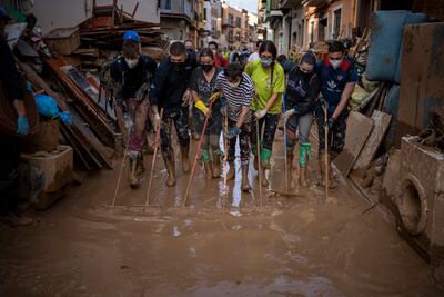 Volunteers and residents clean mud from the streets in an area affected by floods in Paiporta, Valencia. AP