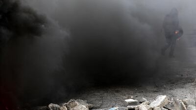 A Palestinian protester holds a tire during clashes with Israeli forces intervening with tear gas during a protest against Israel in the West Bank City of Ramallah. EPA