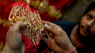 A customer checks rakhis at a shop. AFP