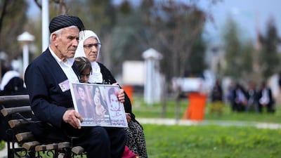 An Iraqi Kurd family holds images of loved ones as they visit in a grave yard for the victims of a gas attack by former Iraqi president Saddam Hussein in 1988.