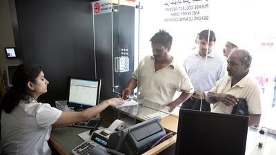 A cashier helps customers exchange money at an UAE Exchange branch on Hamdan Street in Abu Dhabi. Silvia Razgova / The National