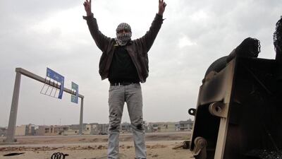 A man shows off the V-sign for victory as he stands on top of a burned-out lorry on the side of the main highway leading west out of Baghdad towards Fallujah on January 5, 2014. The lorries were destroyed during fighting the day before between Iraqi army forces and militants. Sadam El Mehmedy / AFP