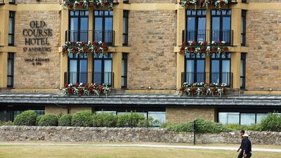 Adrian Meronk and Tiger Woods make their way past the Old Course Hotel. Getty