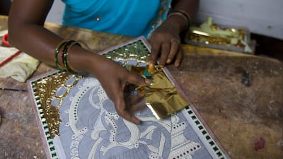 An artist lays gold foil over drawings, before applying strokes of colour