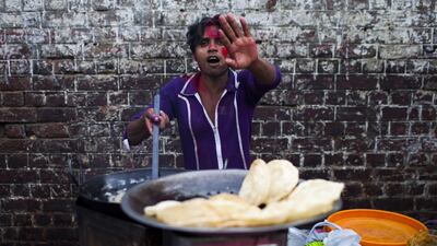 An Indian vendor covered with coloured powder gestures during the festival. Andrew Caballero-Reynolds / AFP Photo