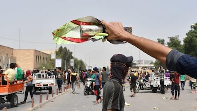 An Iraqi protester holds a smoke grenade fired by security forces amid clashes following an anti-government demonstration in Iraq's southern city of Nasiriyah in Dhi Qar province. AFP