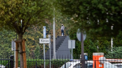 A man who has allegedly threatened to blow himself up stands on a monument in Warsaw, Poland. AP