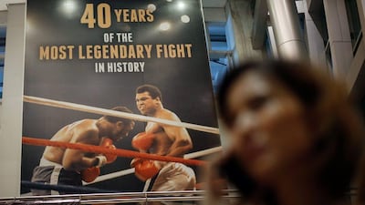 A Filipina uses her mobile phone as she walks past a giant poster at the Ali Mall celebrating 40 years of the heavyweight boxing bout between Muhammad Ali and Joe Frazie in 1975 dubbed 'Thrilla in Manila' at the Araneta Coliseum in Quezon City, northeast of Manila. Mark Cristino /AFP