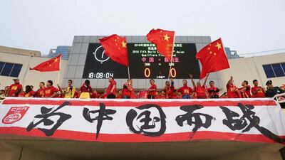Fans cheer ahead of the match between China and Syria. The Chinese characters read, “Fight for China”. Stringer / Reuters