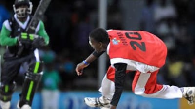 Trinidad and Tobago's Kevon Cooper, right, stretches to field off his own bowling played by Stanford Superstar's batsman Travis Dowlin.