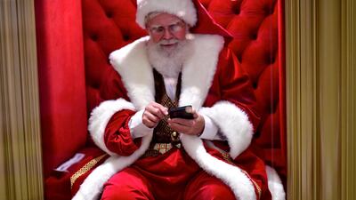 A man dressed as Santa Claus uses his smartphone while awaiting visitors at the Plymouth Meeting Mall in Pennsylvania, US. Reuters