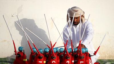 A handler prepares robotic jockeys during the Al Marmoom Heritage Festival.