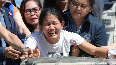 Jessica, sister of Filipina maid Joanna Demafelis whose body was found inside a freezer in Kuwait, cries in front of the wooden casket containing her sister's remains at the international airport in Manila on February 16, 2018. Ted Aljibe / AFP