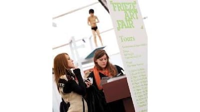 Visitors view the list of exhibits at the Frieze Art Fair 2010.