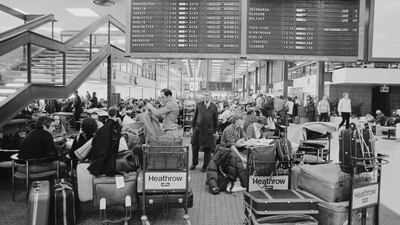 Passengers wait beneath a Heathrow departures board in January 1979. Getty