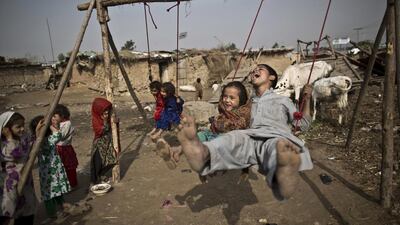 An Afghan refugee boy and his sister on an improvised swing in a poor neighbourhood on the outskirts of Islamabad, Pakistan.