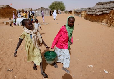 Sudanese refugee girls carry water supplies near a polling station in the refugee camp of Zamzam. AP