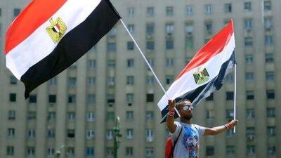An Egyptian man waves two national flags during a protest in Cairo's Tahrir Square on Sunday, vowing to keep up their sit-in which began on July 8, despite a series of concessions by the Egyptian prime minister. Mohammed Hossam / AFP Photo