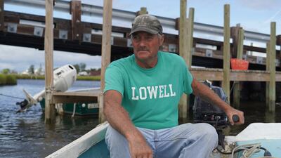 Mr Eskridge drives his small boat through shallow water as he heads to his crab shanty.