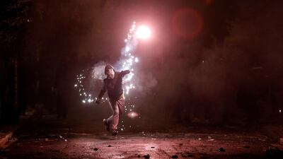 A hooded protester throws a flare during clashes following a rally marking the 44th anniversary of a 1973 student uprising against the military dictatorship that was ruling Greece, in Athens, Greece. Alkis Konstantinidis / Reuters