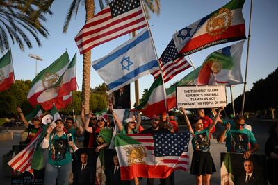 People hold pre-revolutionary Iranian flags as they protest outside Carson Sports Park before Iran’s training session in Los Angeles. AFP