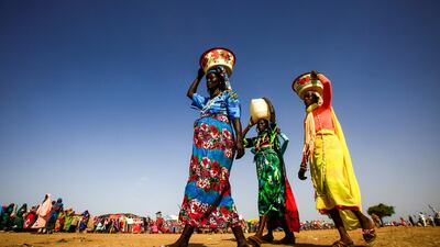 Sudanese women carry buckets and containers of water on their heads in the town of Umm al-Qura, northwest of Nyala in South Darfur province. According to Amensty International Noura Hussein Hammad, 19, was handed a death sentence by a Sudanese court for killing the man her father forced her to marry. Ashraf Shazly / AFP