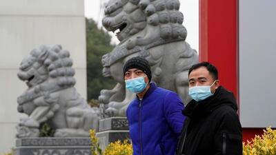 Chinese men wearing masks stand near stone lions across from the Wuhan Jinyintan Hospital where a team from the World Health Organization visited in Wuhan in central China's Hubei. AP Photo