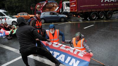 A member of the public pulls a banner away from protesters as Insulate Britain activists block a motorway junction near Heathrow Airport. Reuters