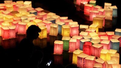 People watch floating paper lanterns on the Motoyasu River at Hiroshima Peace Memorial Park in Hiroshima, western Japan. Kiyoshi Ota / EPA
