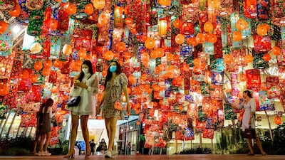 People walk under festive decorations for the upcoming Lunar New Year outside a shopping mall in Bangkok, Thailand. AFP