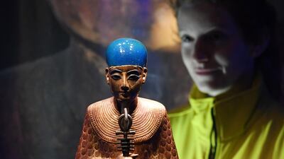 A gallery employee poses for photographers next to a statue of Ptah, dated 1336-1326 BC, from the reign of Tutankhamun, during the press preview for the 'Tutankhamun: Treasures of the Golden Phaorah' exhibition at the Saatchi Gallery in Chelsea in London, Britain, 01 November 2019. EPA