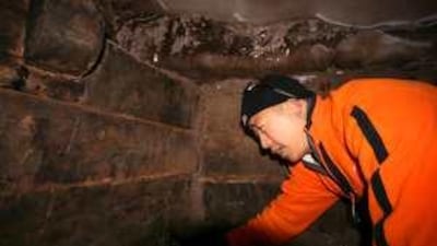 A member of a group of Chinese and Turkish evangelical explorers examines wooden beams inside a compartment of a structure that they claim is the biblical vessel for Noah's Ark.