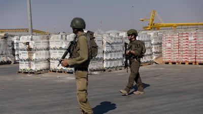 Israeli soldiers pass by humanitarian aid packages waiting to be picked up on the Palestinian side of the Karam Abu Salem crossing point between Israel and southern Gaza, in July 2025. Getty