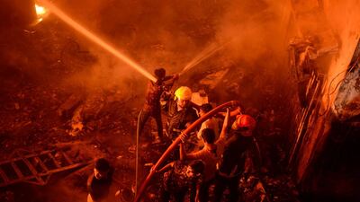In this Wednesday, Feb. 20, 2019, photo, firefighters try to douse flames in Dhaka, Bangladesh. A devastating fire raced through at least five buildings in an old part of Bangladesh's capital and killed scores of people. (AP Photo/Mahmud Hossain Opu)