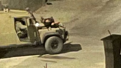 A man is seen lying on the bonnet of a military vehicle during an Israeli raid on Tulkarm refugee camp in the occupied West Bank on Tuesday. Photo: Wafa