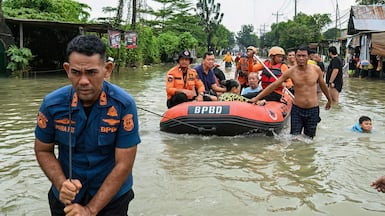 Rescuers ferry the elderly after flooding in Medan, North Sumatra. AFP