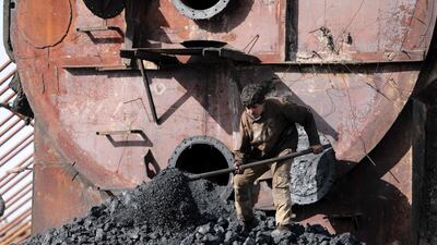 A boy shovels coal at a makeshift oil refinery near Tarhin, in the northern countryside of Aleppo, Syria. Many children work at these sites, under appalling conditions. AFP