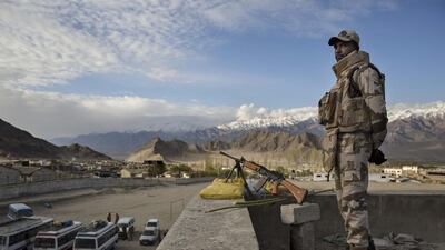 Security force soldier stands guard on a rooftop at a central collection point for distribution of voting machines for polling stations.